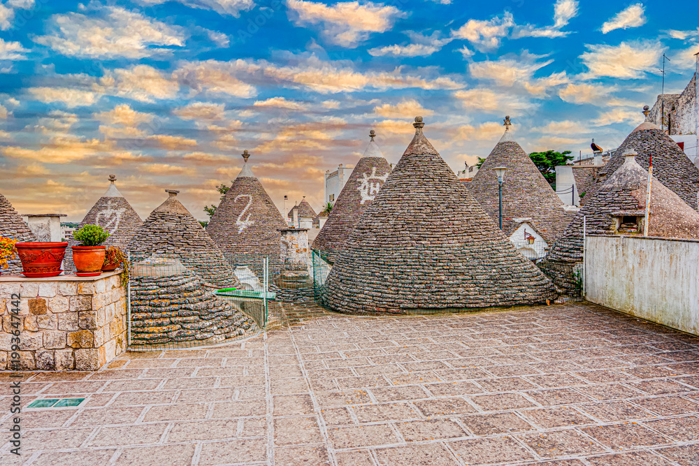 Fototapeta premium Alberobello miasto we Włoszech, słynie z unikatowych form budownictwa – domów typu trulli, które są okrągłe i mają stożkowate dachy z kamienia.