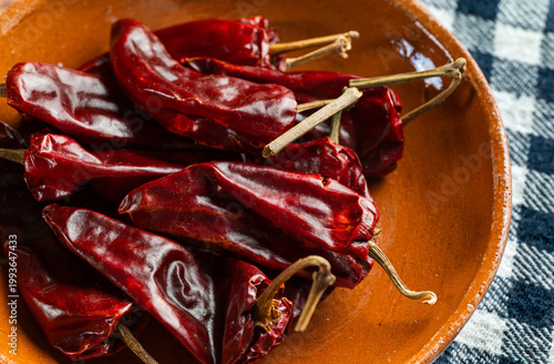 Bilde på lerret Macro shot of red dried guajillo chilies in handcrafted clay bowl