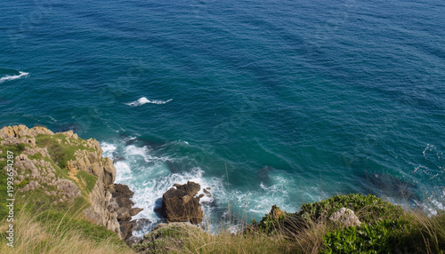 A serene ocean landscape with rocky cliffs and waves crashing