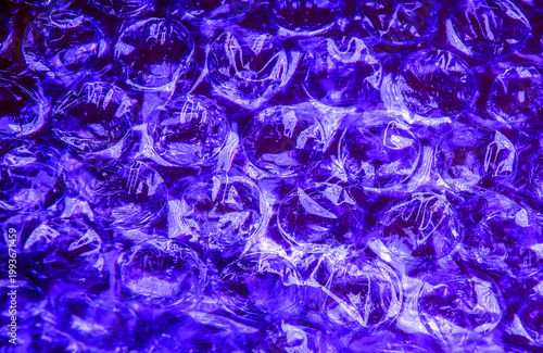 a background of deep blue-violet color, made up of many small, shiny, transparent plastic bubbles