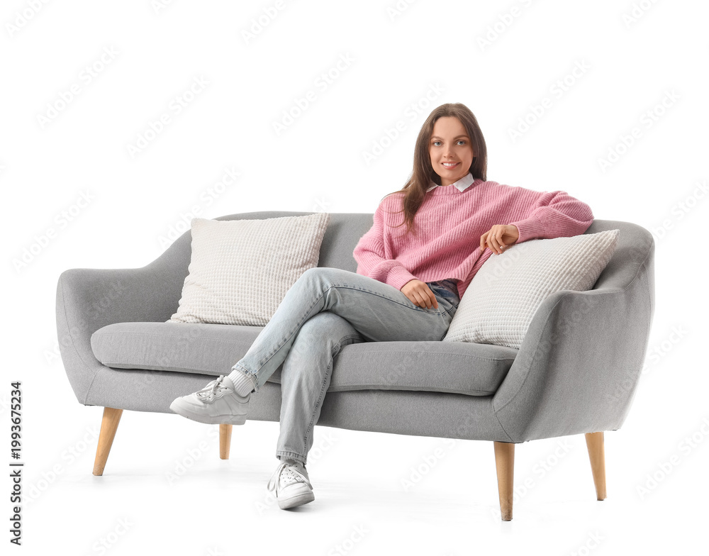 Obraz premium Young woman sitting on grey couch against white background