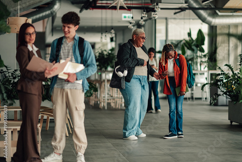 Obraz na płótnie Diverse students and a faculty member interacting in a bright university hallway