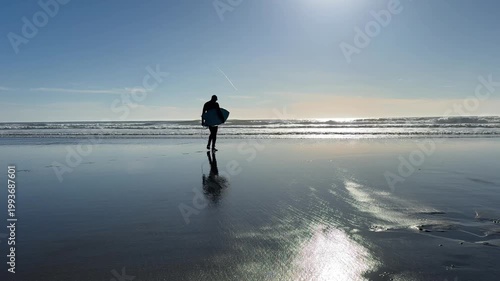 Silhouette of Surfer Entering Ocean with Surfboard