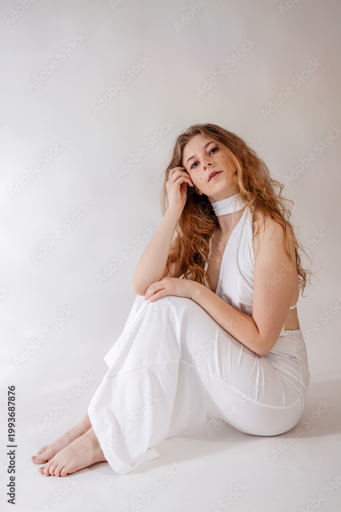 Fototapeta premium Stunning portrait of a beautiful young woman with long voluminous curly hair posing in a professional photo studio, beauty and fashion concept, Prague, Czech Republic, June 2025