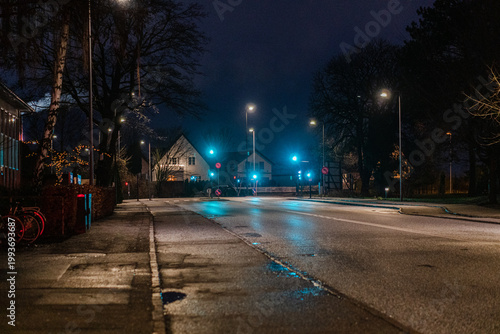 Night city street with traffic lights and reflections on wet asphalt.