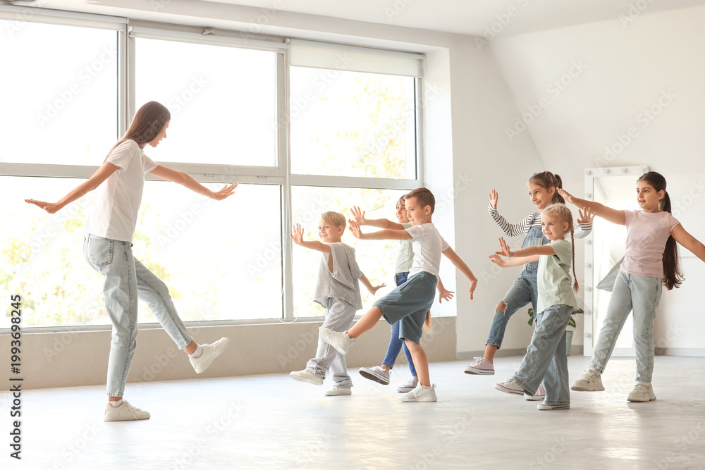 Fototapeta premium Group of little children with teacher dancing in studio