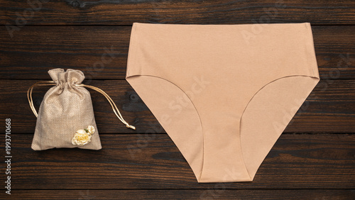Foto Beige High-Waist Underwear and Burlap Bag on Wooden Background for Fashion and E