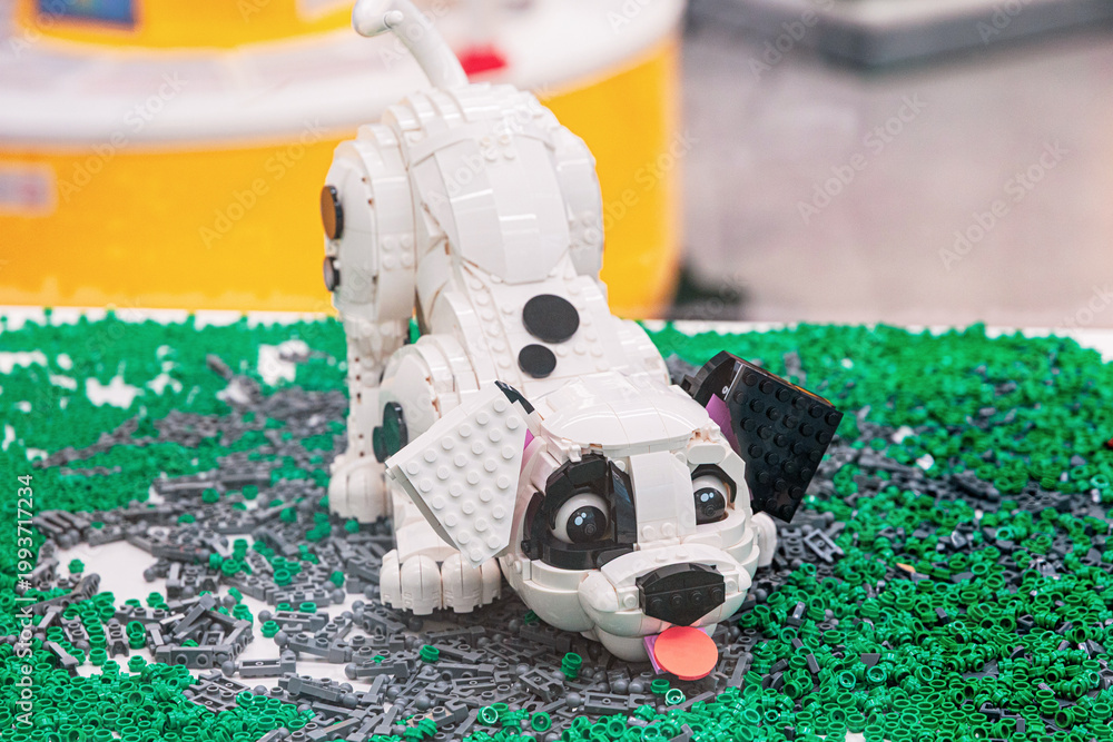 Fototapeta premium 14 January 2026, Dubai, UAE: Dalmatian puppy statue made from Lego bricks, standing on a surface covered with miniature green toy elements