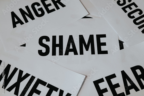 Various words representing different emotions are arranged on a surface, including shame, anger, and anxiety. This still life setup highlights complex human feelings and their visual expression