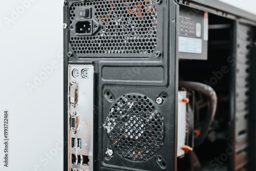 A computer tower is positioned against a neutral background, featuring visible dust accumulation on the back panel
