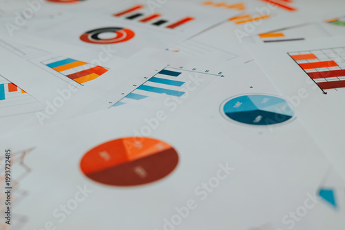 Various charts and graphs are arranged on a flat surface, illustrating data analysis for business growth. The visuals display different colors and shapes, emphasizing key metrics and trends