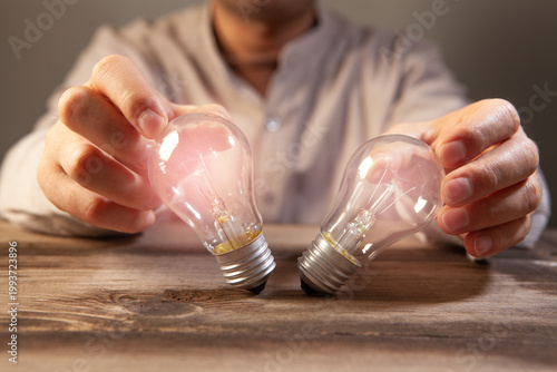 Close up of a person holding a light bulb in his hand.