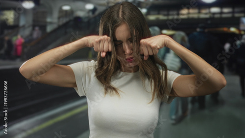 Photos Woman in white t shirt with clenched fists on busy underground railway station platform; frustration