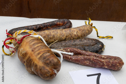 Assorted cured sausages on white surface with rustic presentation