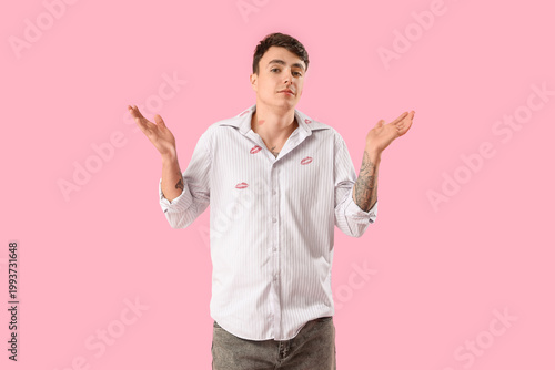 Photos Embarrassed man with kiss marks on his shirt against pink background