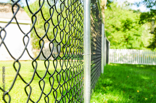 Schilderij op canvas A chain link fence extends across a residential yard, a functional and familiar boundary marker of American neighborhood life