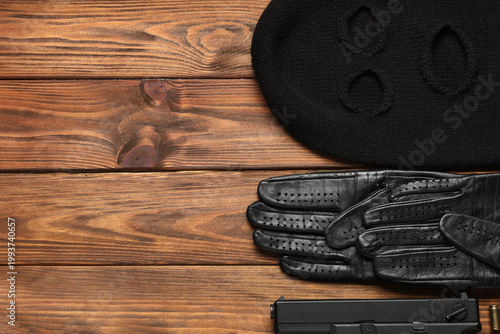 Fotografía Balaclava with gloves and gun on wooden background with space for text