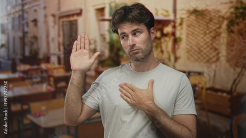 Картината върху платно Man with right hand raised palm and left hand over chest in street cafe terrace outdoors, showing raised palm oath gesture; sincerity pledge