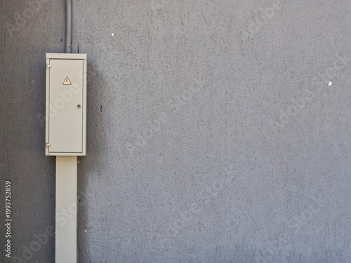 Exterior Electrical Junction Box with Hazard Symbol on Grey Wall — Urban Infrastructure Electricity Safety Concept with Copy Space