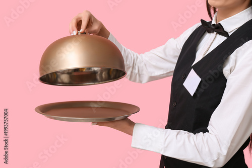 Fotografie Waitress with metal tray and cloche on pink background, closeup