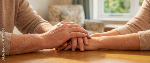 support comfort care holding hands empathy warmth cozy home connection clasped hands above a wooden table show reassurance trust and emotional closeness for counseling wellness and home care themes