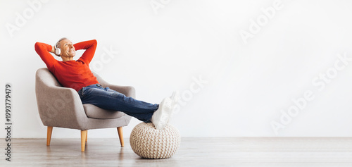 Canvastavla A senior man sits in a comfortable chair listening to music with headphones