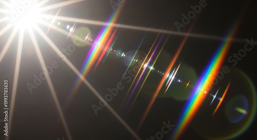Bright light with colorful rainbow lens flares and beams on dark background