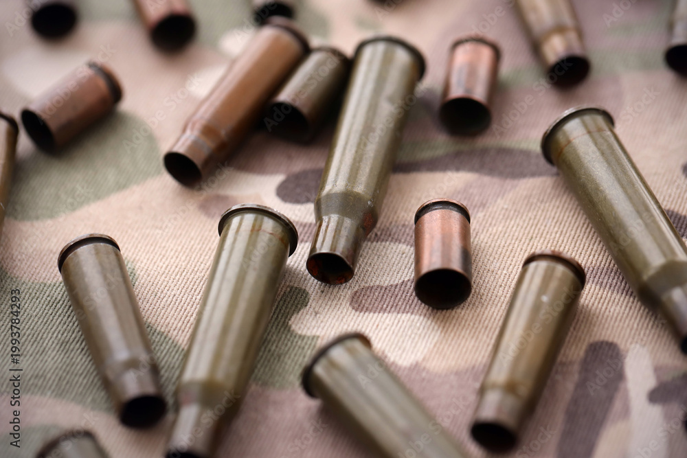 Naklejka premium Big amount of shells cartridges from assault rifle bullets on old camouflage fabric