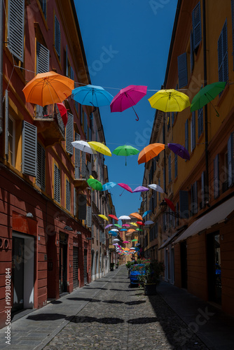 Colorful umbrellas in the city .City street in Modena, Italy with rainbow colored umbrellas overhead, vibrant urban scene, summer atmosphere, travel destination