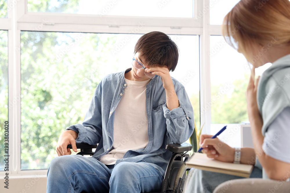 Fototapeta premium Sad teenage boy in wheelchair at psychologist's office