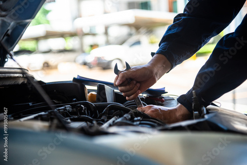 фотографія Close up Mechanic man hands repairing car auto repair shop uses jack change tyre
