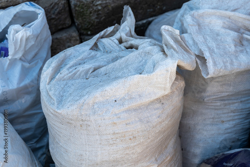 Foto Several large bags filled with waste materials are stacked on the ground next to