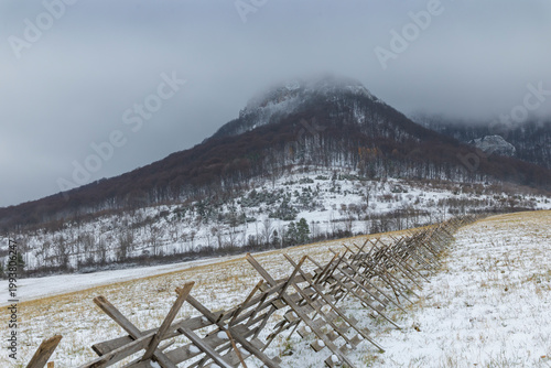 Wooden fence line leading to foggy winter mountain