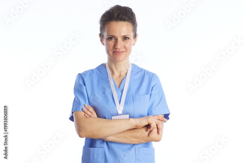 A professional female medical worker in blue scrubs stands with arms crossed, conveying reliability, expertise, and a welcoming approach to healthcare.