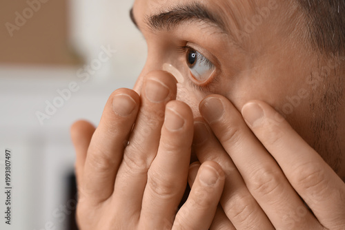 Canvastavla Young man putting in contact lenses at home, closeup