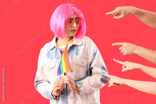 Foto People pointing at upset young woman with LGBT flag on red background