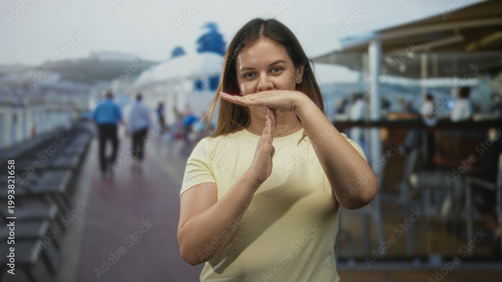 Fototapeta premium Young woman with hands making time out gesture on sunny cruise ship deck near railing; calm pause reflection.