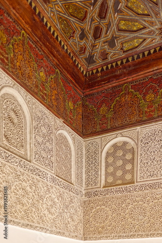 Carved-painted cedar wood ceiling, lavishly sculpted stucco wall, corner of the Ben Youssef Madrasa courtyard doorway vestibule. Marrakesh-Morocco-311
