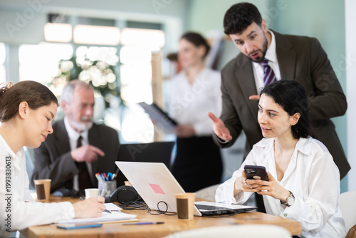 Canvas Print Male boss chastises female subordinate for idleness and scrolling of phone, social networks and stealing personal and working time