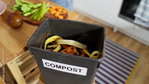 Woman throwing kitchen scraps into compost bin.