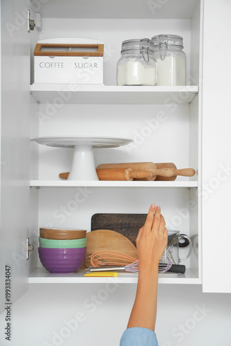 Woman opening kitchen cupbo...