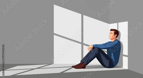 Man sits on floor in corner with shadows from windows in a room during the daylight hours