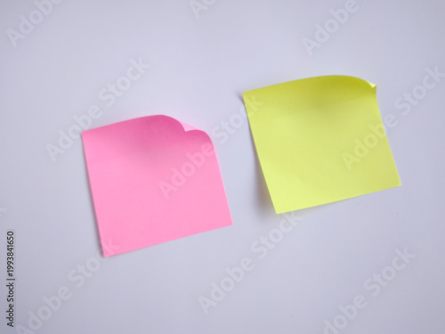 Colorful sticky notes. Yellow and pink post it paper note on a white wall background with empty space.