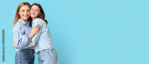 Beautiful mature woman with her daughter hugging on blue background. Mother's...