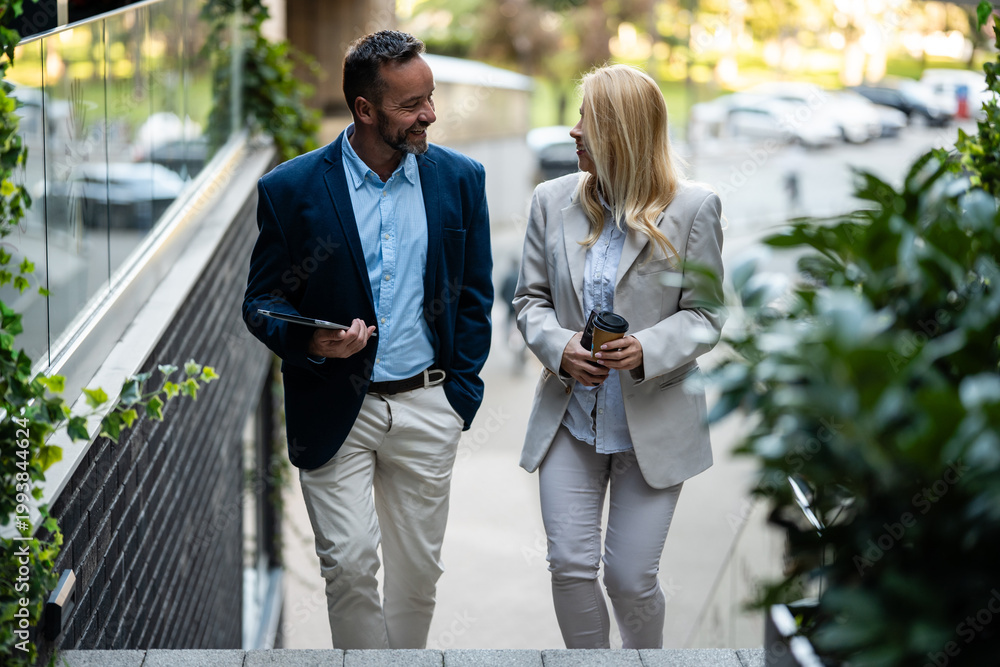 Fototapeta premium Business colleagues walking and talking casually outdoors