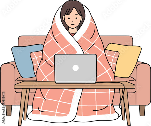 A woman wrapped in a blanket holds a warm drink and an open laptop
