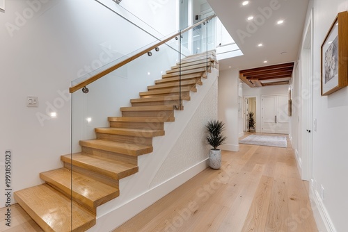 Bright modern home interior with a wooden staircase, glass railing, and light hardwood floors