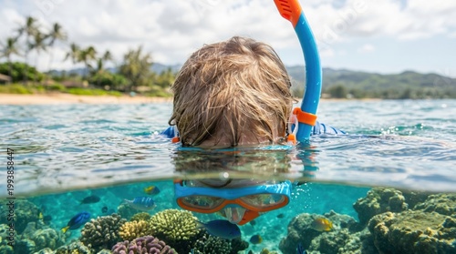 A child snorkels above vibrant coral reefs, observing colorful fish in clear blue water. A serene tropical beach is visible in the background.