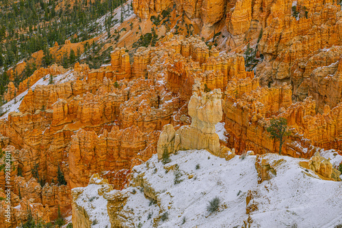 Bild auf Leinwand Close-up of intricate orange hoodoos partially covered in snow with scattered ev