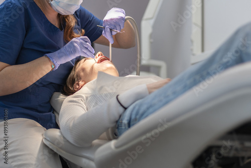The dentist cleans the patient's mouth.